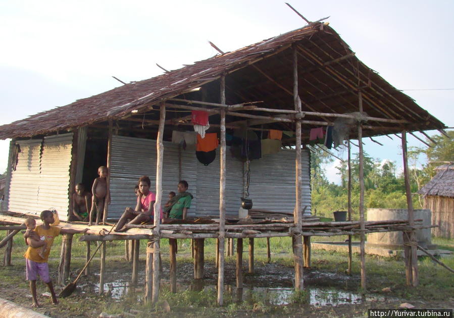 Дом и за ним колодец, у которого можно набрать воды и умыться Джайпура, Индонезия