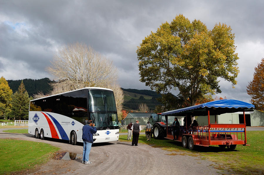 Сельскохозяйственное шоу Agrodome. Туристы пересаживаются с автобуса на трактор Роторуа, Новая Зеландия