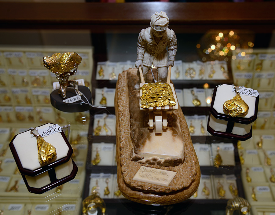 Настольная фигурка горняка, везущего тачку золотых самородков, выполненная сама из бивня мамонта и водруженная на подставку из полудрагоценного камня. Магадан, Россия