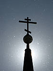 Крест колокольни Рождественской церкви в лучах солнца и в парящем тополином пухе.