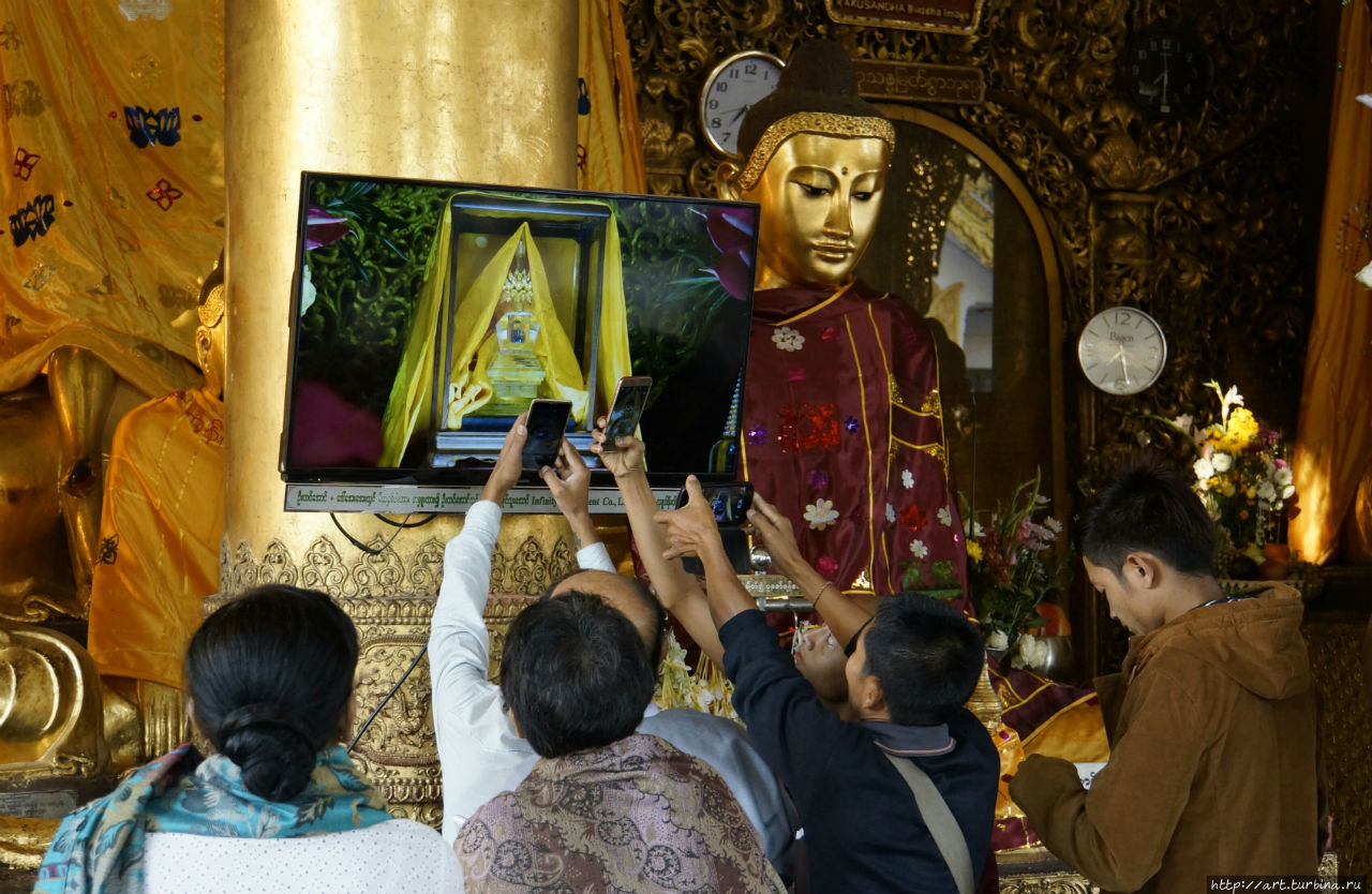Те, кому не доставалось мест в первых рядах, бросались фотографировать на телефоны  транслируемое на тв изображение святыни. Янгон, Мьянма