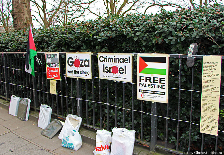 по левой стороне улицы начался Грин парк, на его заборе  то какие-то лозунги, например атнтиизраильские... Лондон, Великобритания