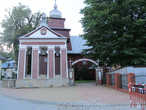 Перед костелом находится колокольня, возведенная в 1806 г. в виде каменных столбов, спаренных треугольным фронтоном, в котором помещен герб Тылича.