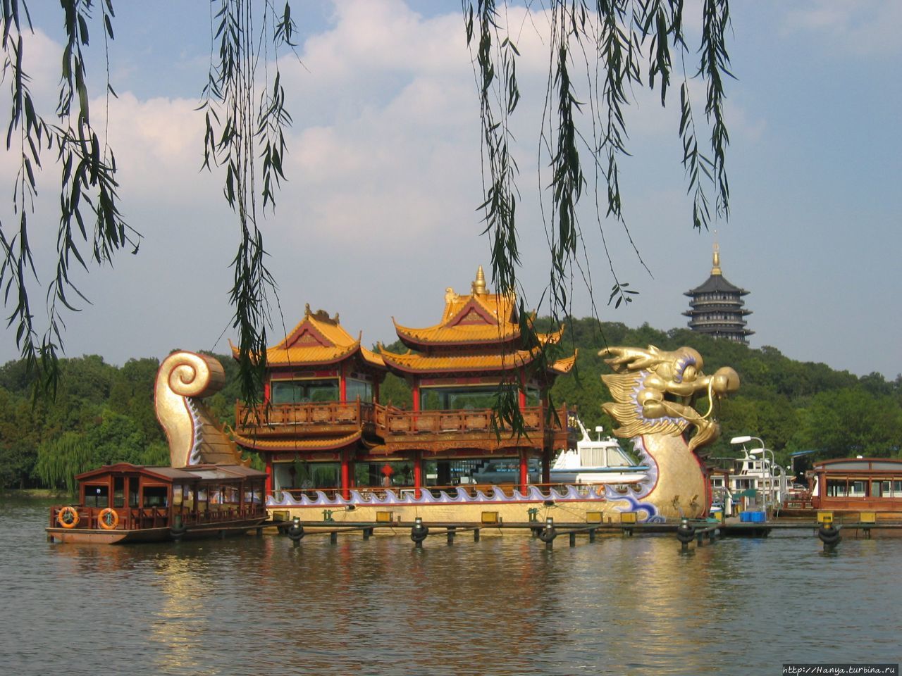 Озеро Сиху. Плавучий ресторан  в виде  старинного китайского корабля с головой дракона. Вид на храм полководца Юэ Фэя Ханчжоу, Китай
