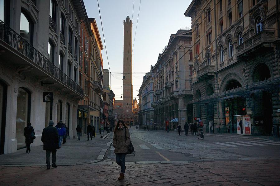 В конце улицы видна башня Торре Ассинелли Болонья, Италия