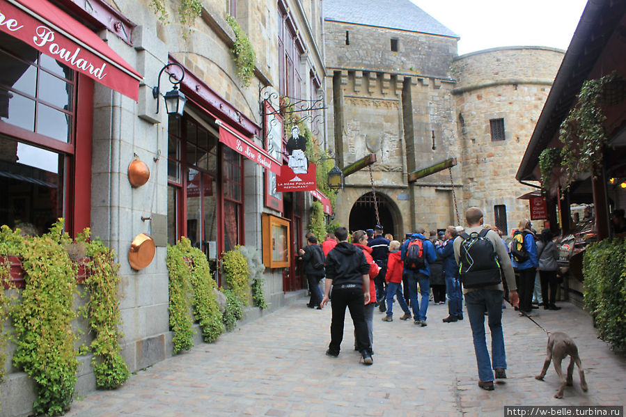 Впереди Королевские Врата. Между Бульварными и королевскими воротами находится небольшой двор в котором расположены кафе, а также знаменитый ресторан  La Mere Poulard. Мон-Сен-Мишель, Франция