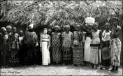 Bondo Initiate in White Kaolin at Bitema in Nongowa Chiefdom — 1969.
In the center is a young Bondo initiate covered in a white clay during one of the stages of her initiation. To her right is the Bondo Masquerade which was known locally as the Bondo Devil.
Location : Bitema Nongowa — Kenema District — Eastern Province