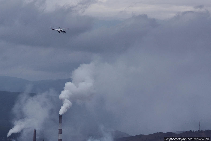 Вертолет пролетает на дымом заводских труб. Карабаш, Россия