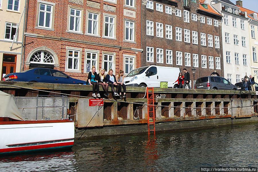 На берегах сидят люди, скорее всего, туристы Копенгаген, Дания
