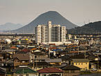 Холм-гора Сануки Фудзи, прекрасная, как боже ж ты мой, и белый мэншн на её фоне. Я не пытался снова высказаться по поводу японской урбанизации и современной архитектуры. Оно само получается, не деться от этого никуда. Это мы въехали, между тем, в Маругамэ.