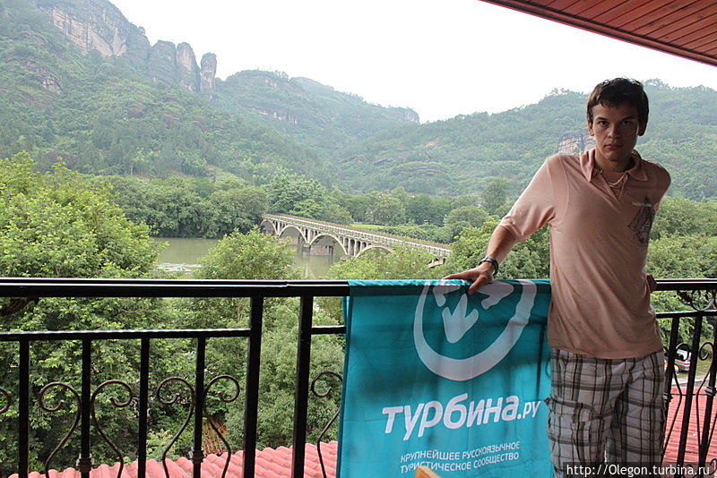 Алексей Коньков с флагом Турбины на фоне реки Девяти Изгибов в Уишане Уишань, Китай