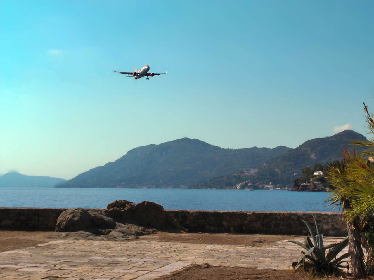 Самолет летит в Канóни Канони, остров Корфу, Греция