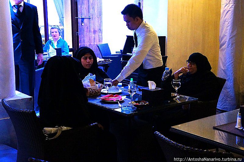 Официант, явно филиппинец, обслуживает местных тетенек. Доха, Катар