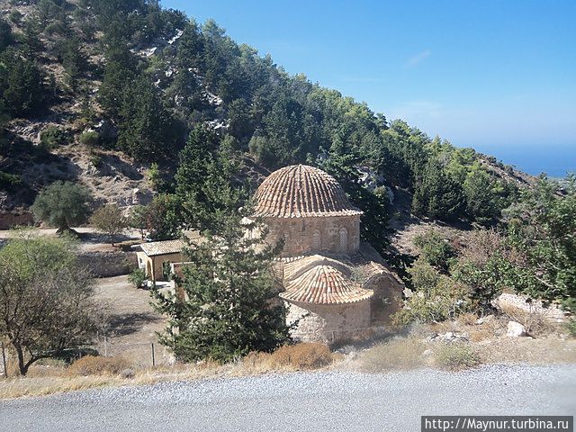 Монастырь примостился  у основания холмов, как в гнездышке. Кипр