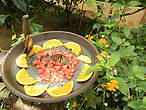 Среди цветов расставлены тарелки с кусочками свежих фруктов. Завтрак подан...