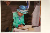 Елизавета II делает запись в книге посетителей.
