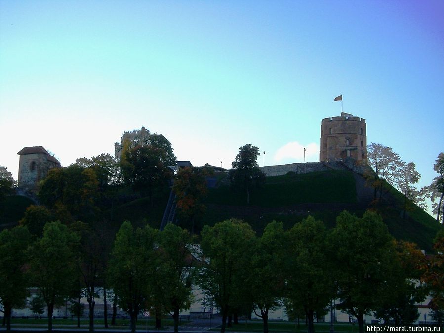 Тёмный силуэт башни Гедиминаса на вершине крутого холма постепенно приобретает свой кирпичный окрас, и чётче становятся полосы национального флага Вильнюс, Литва