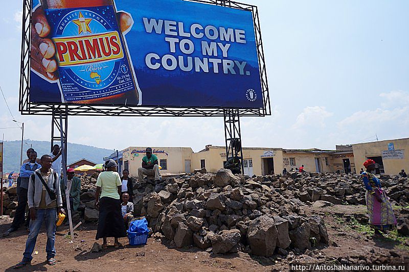 Реклама пива Примус производства БраЛиРвы на пограничном переходе. Снизу куча вулканического камня Гисеньи, Руанда
