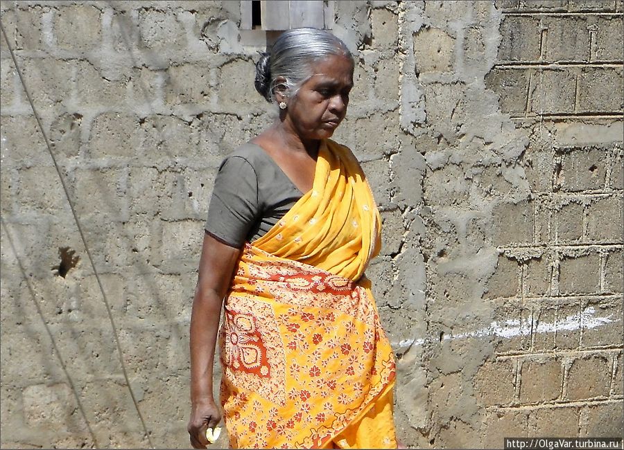 Трудно представить себе пожилую россиянку в наряде такой расцветки, а на Шри-Ланке яркие цвета в одежде сплошь и рядом. Похоже, что стена сохранила следы прошедшей войны...