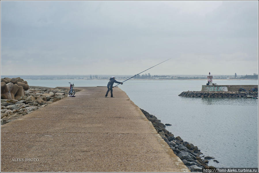 Как и положено для таких мест — рыбаки. А справа — небольшой маяк при входе в бухту... Эль-Джадида, Марокко