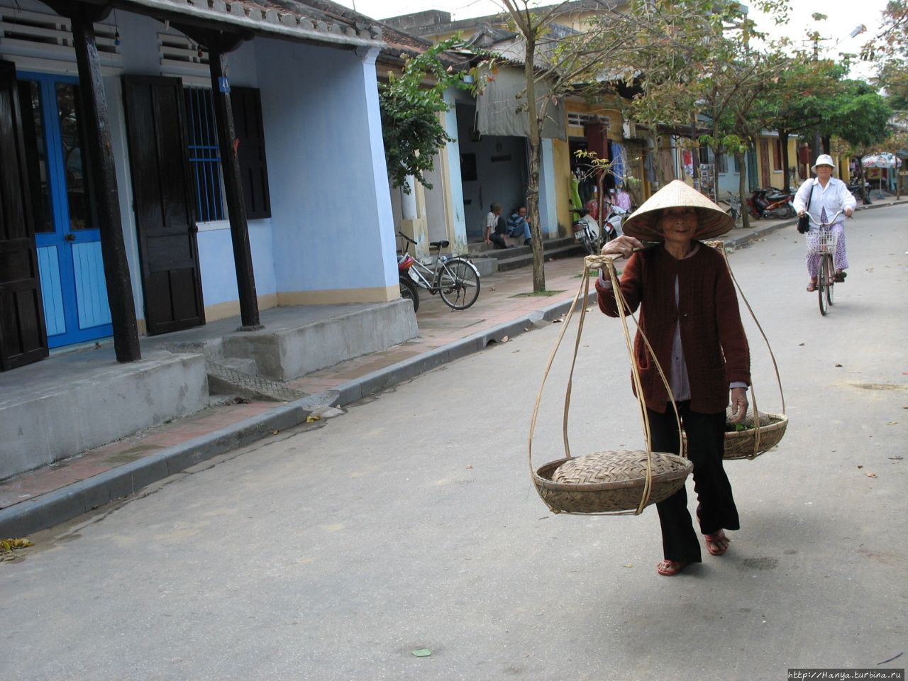 Хойан. Старая вьетнамка с   коромыслом и корзинами Хойан, Вьетнам
