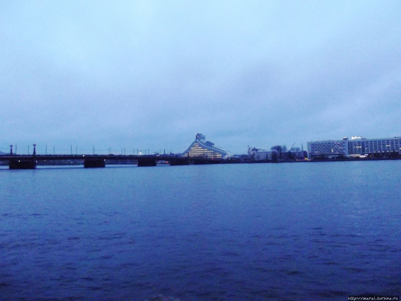 По ту сторону Рижского замка — река Даугава. Вы видите Каменый мост (1957) и Замок Света (Национальная библиотека) на другом берегу. Рига, Латвия