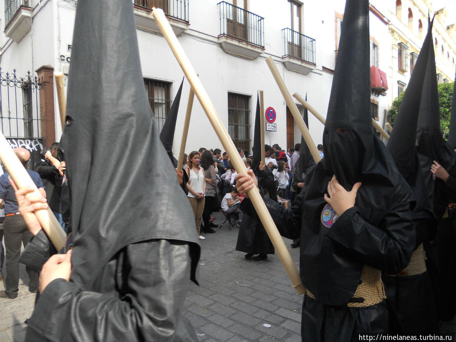 участники процессии, одетые в специальную тунику (la tunica) и (el capirote)-высокий головной убор с прорезями для глаз Севилья, Испания