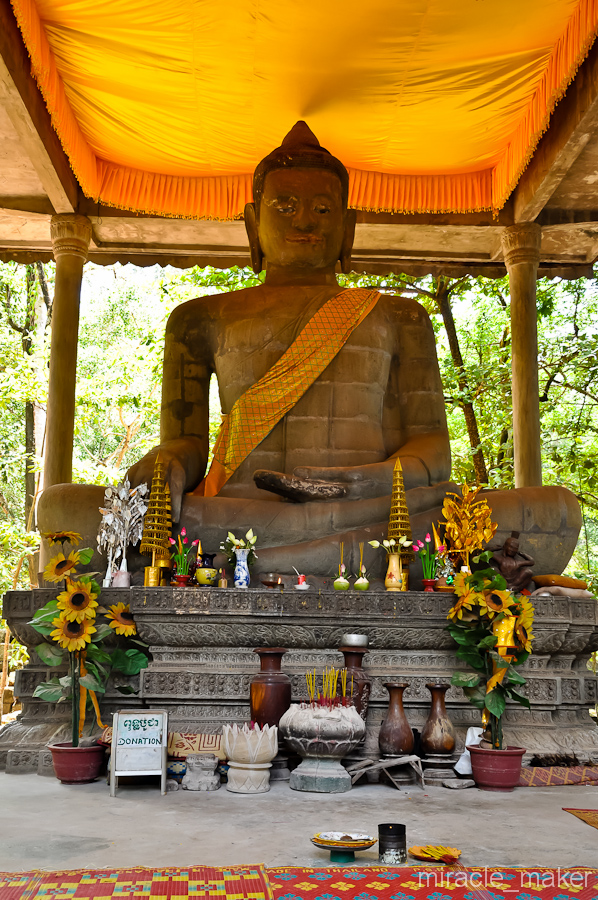Среди леса повстречалась действующая и очень ухоженная статуя Будды. У смотрительницы этой статуи, пожилой монахини, можно получить благословение в виде небольшой молитвы и красной ниточки на руку. Ангкор (столица государства кхмеров), Камбоджа
