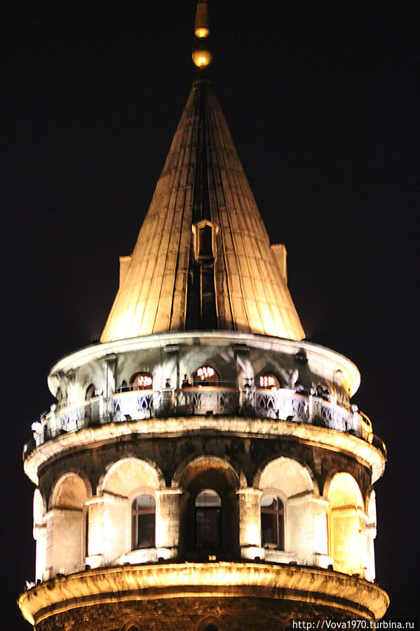 Вид на смотровую площадку Галатской башни с туристами вечером.