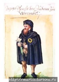 Средневековый купец-иудей (15 век), в руках кошель для денег и чеснок. Чеснок — символ ШУМ-городов ( шум — на иврите чеснок). foto Wiki Шпайер, Германия