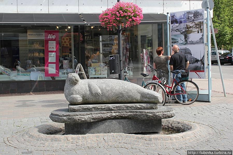 Каменная нерпа лежит на небольшом постаменте посреди одной из пешеходных улиц города. Лаппеенранта, Финляндия