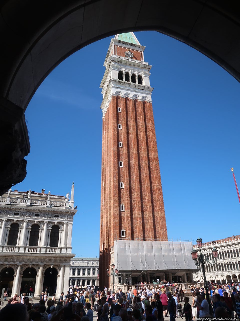 Ожидаем гида под арками (верхняя массивная часть Дворца дожей покоится на лёгких ажурных арках) с видом на колокольную башню (кампанилу) при соборе Святого Марка в Венеции и отправляемся на экскурсию. Венеция, Италия