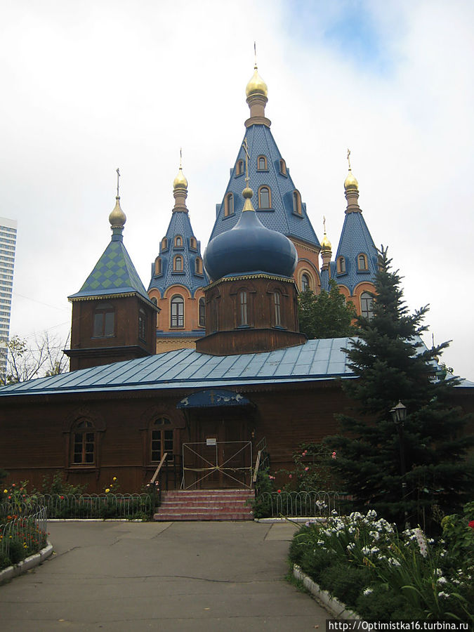 В марте 1997 г. построена деревянная церковь-часовня.
Фото сделано 4 сентября 2011. На переднем плане — деревянная церковь, с которой началось возведение храма. Москва, Россия