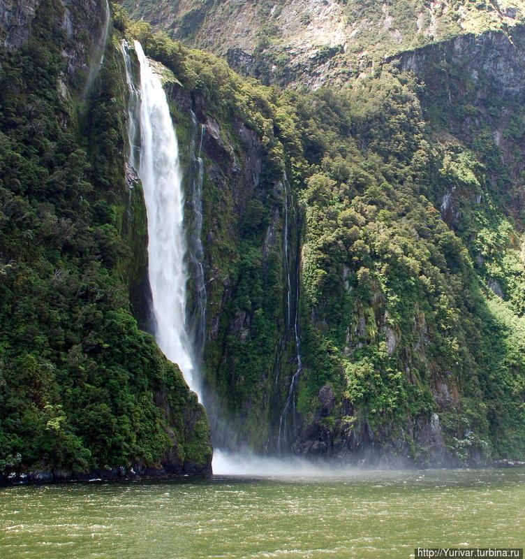 Под поток водопада Stirling Falls некоторые капитаны к радости туристов заводят нос своего судна Фьордленд Национальный Парк, Новая Зеландия