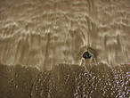 Волны рисуют причудливые орнаменты на мраморном золотисто-чёрном песке