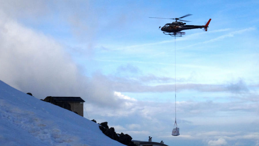 Вертолет выполняет регулярные рейсы по доставке грузов и людей. Монблан гора (4810м), Франция