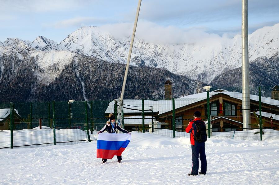 Зрители фотографируются на фоне горной олимпийской деревни Красная Поляна, Россия