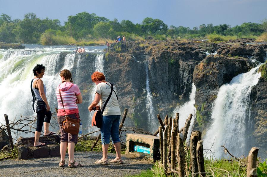 Народ фотографируется на фоне замбийской стороны водопада Виктория-Фоллс, Зимбабве