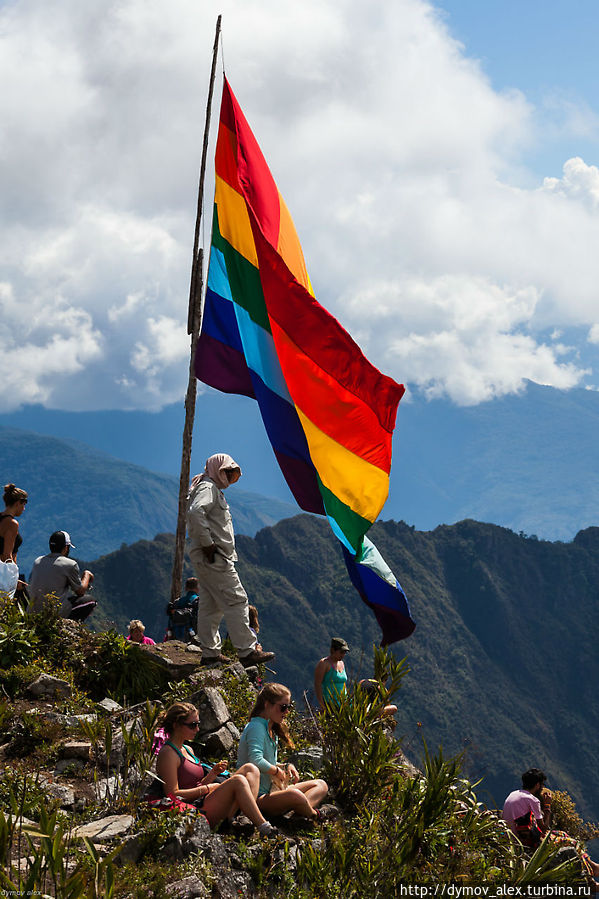 Под флагом — местный сотрудник. Считает, кто упал, чтобы внизу вычеркивали Мачу-Пикчу, Перу