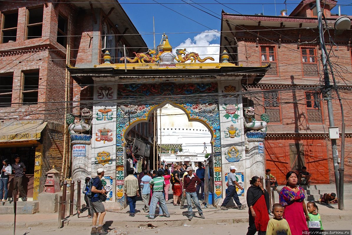 Ворота — новое дополнение, построенное в традиционном тибетском дизайне с восемью благоприятными символами с двух сторон ворот и некоторыми миниатюрными chaityas на вершине. Из интернета Катманду, Непал