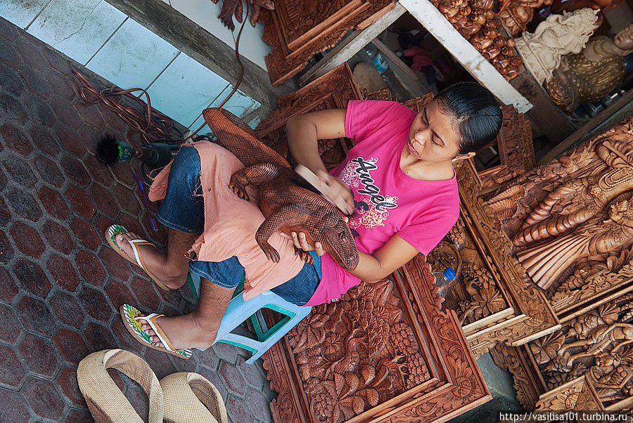 Девушка шкурит деревянного варана Бали, Индонезия