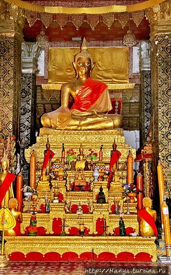 Ват Тхат Луанг. Гребешковый мотив стен, свечи и цветы в алтаре. Фото из интернета