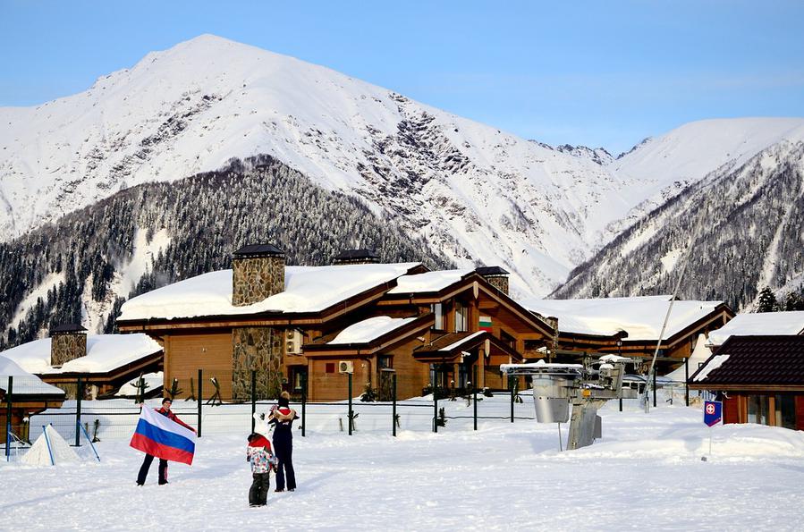 Зрители фотографируются на фоне горной олимпийской деревни Красная Поляна, Россия