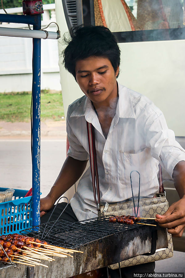 Парень продает какие-то жареные колбаски Камбоджа