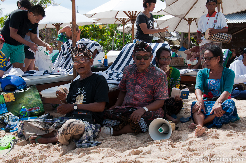 В тени пляжных зонтов расположились специальные люди, читающие молитвы в громкоговоритель. Бали, Индонезия