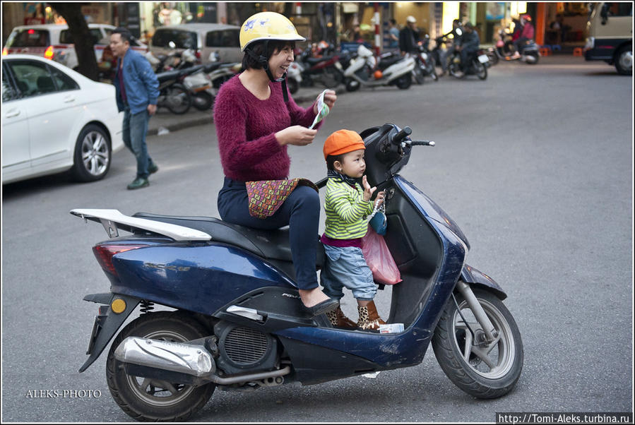 На мотоциклах здесь ездят все — от мала до велика. Дети с самого раннего возраста привыкли к двухколесным средствам передвижения. Вот как раз местная мадам надевает традиционную маску... Ханой, Вьетнам
