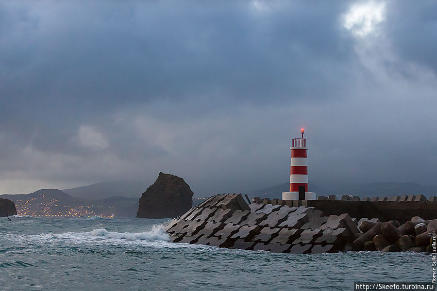 Маяк на закате, на заднем плане виднеется остров Файял и город Орта.