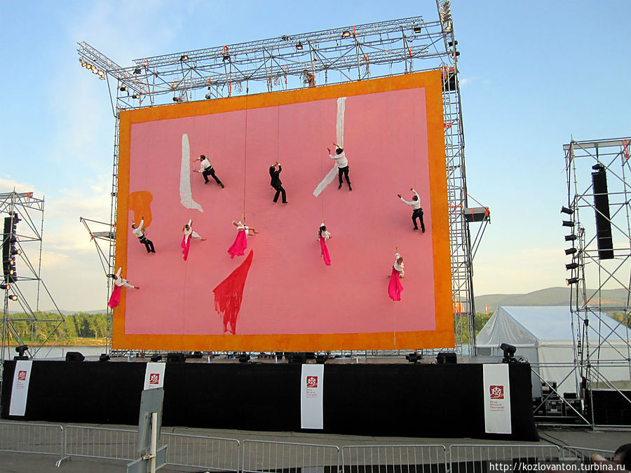 Удивительное зрелище, когда артисты в альпинистской обвязке на вертикально-закрепленном экране исполняли невероятные танцы и разыгрывали драматические эпизоды.