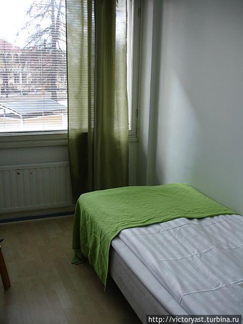 Кровать в номере и маленькая шторка на окне Коувола, Финляндия