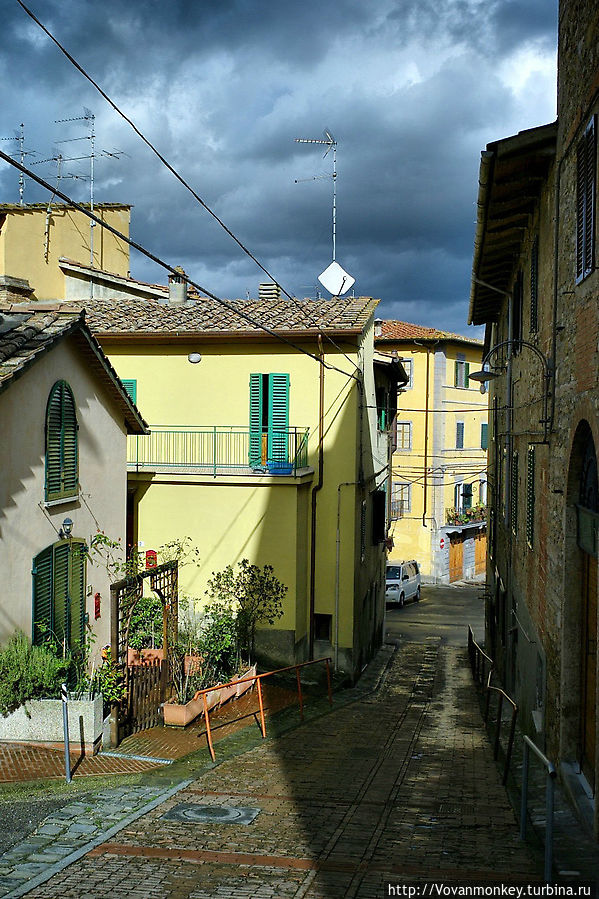 Какая то улочка ведёт вверх, со стрелкой и надписью Panorama Поджибонси, Италия